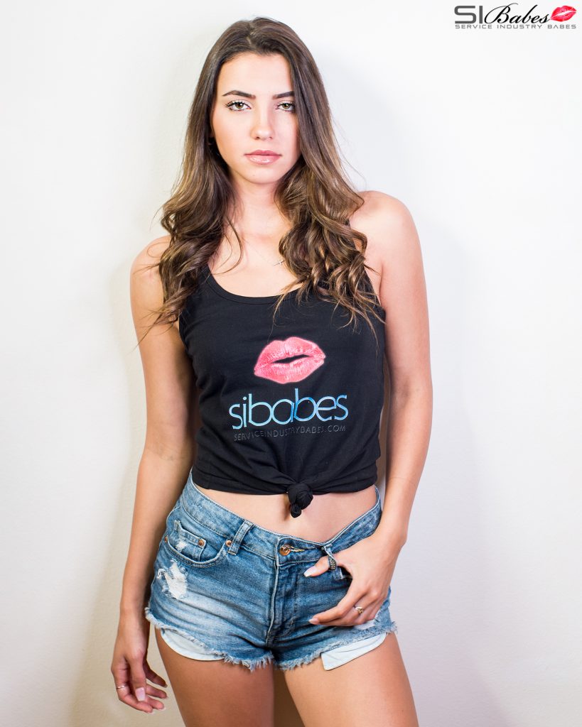 SIBABES studio portrait of a woman in a black logo top against a light backdrop.