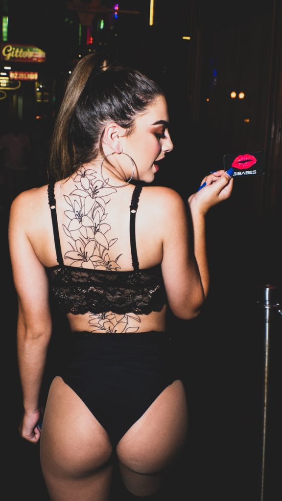 Woman holding a SIBABES card in a nightlife venue, from the SIBABES archive.